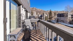 Un balcone con pavimento in legno, ringhiere metalliche e una sedia.