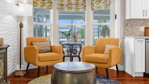 A room with two yellow armchairs, a round coffee table, a floor lamp, and a view of the outside through large windows. - Garry's Landing! Canal front home with boat dock! (Bradenton)