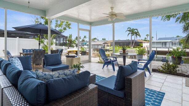 A covered outdoor seating area with wicker furniture, umbrellas, and potted plants. - Garry's Landing! Canal front home with boat dock! (Bradenton)