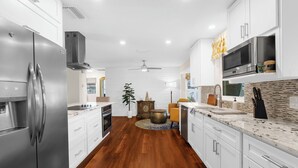 A modern kitchen with white cabinets, stainless steel appliances, and a wooden floor. - Garry's Landing! Canal front home with boat dock! (Bradenton)