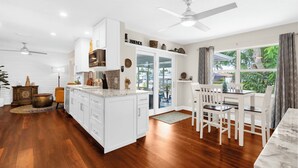 A modern kitchen with white cabinets, a marble countertop, and a dining area with white chairs. - Garry's Landing! Canal front home with boat dock! (Bradenton)