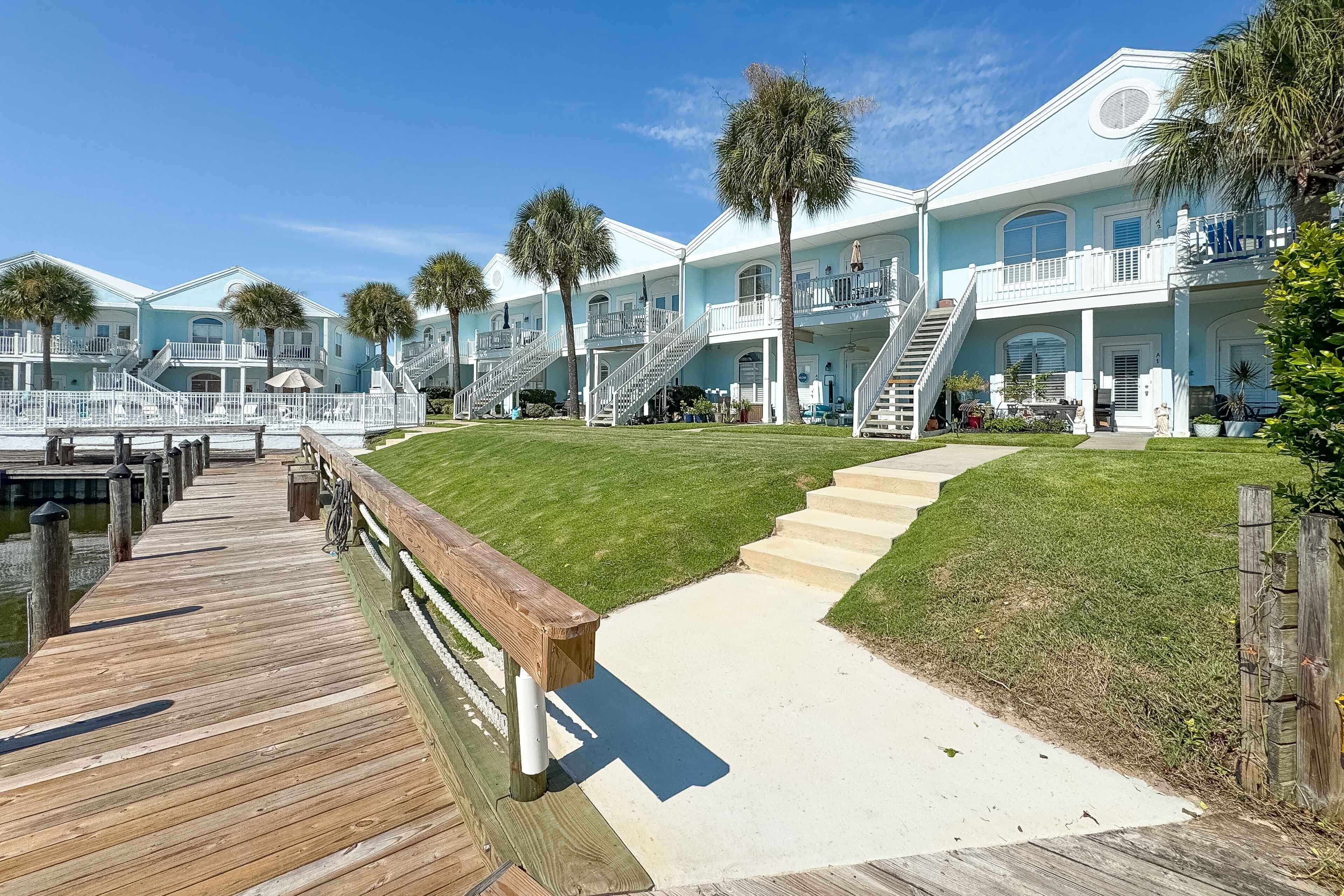 A waterfront property with multiple buildings, a wooden dock, and a well-maintained lawn.