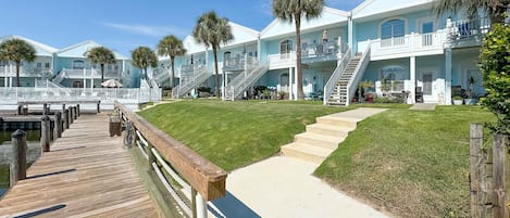 A waterfront property with multiple buildings, a wooden dock, and a well-maintained lawn.