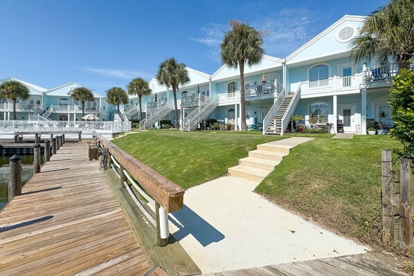 A waterfront property with multiple buildings, a wooden dock, and a well-maintained lawn.