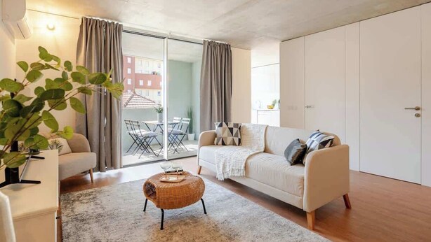A modern living room with a sofa, a coffee table, and a potted plant. - Modern Family Flats w/ Terrace by HostWise (Porto)