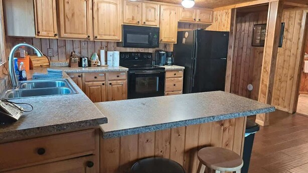 Une cuisine avec des meubles en bois, un plan de travail en granit, un four à micro-ondes, une cuisinière et un réfrigérateur.