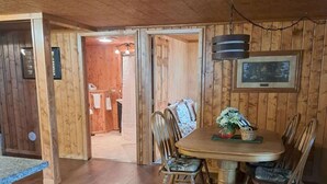 Un intérieur en bois comprenant une table à manger, des chaises et un coin cuisine.