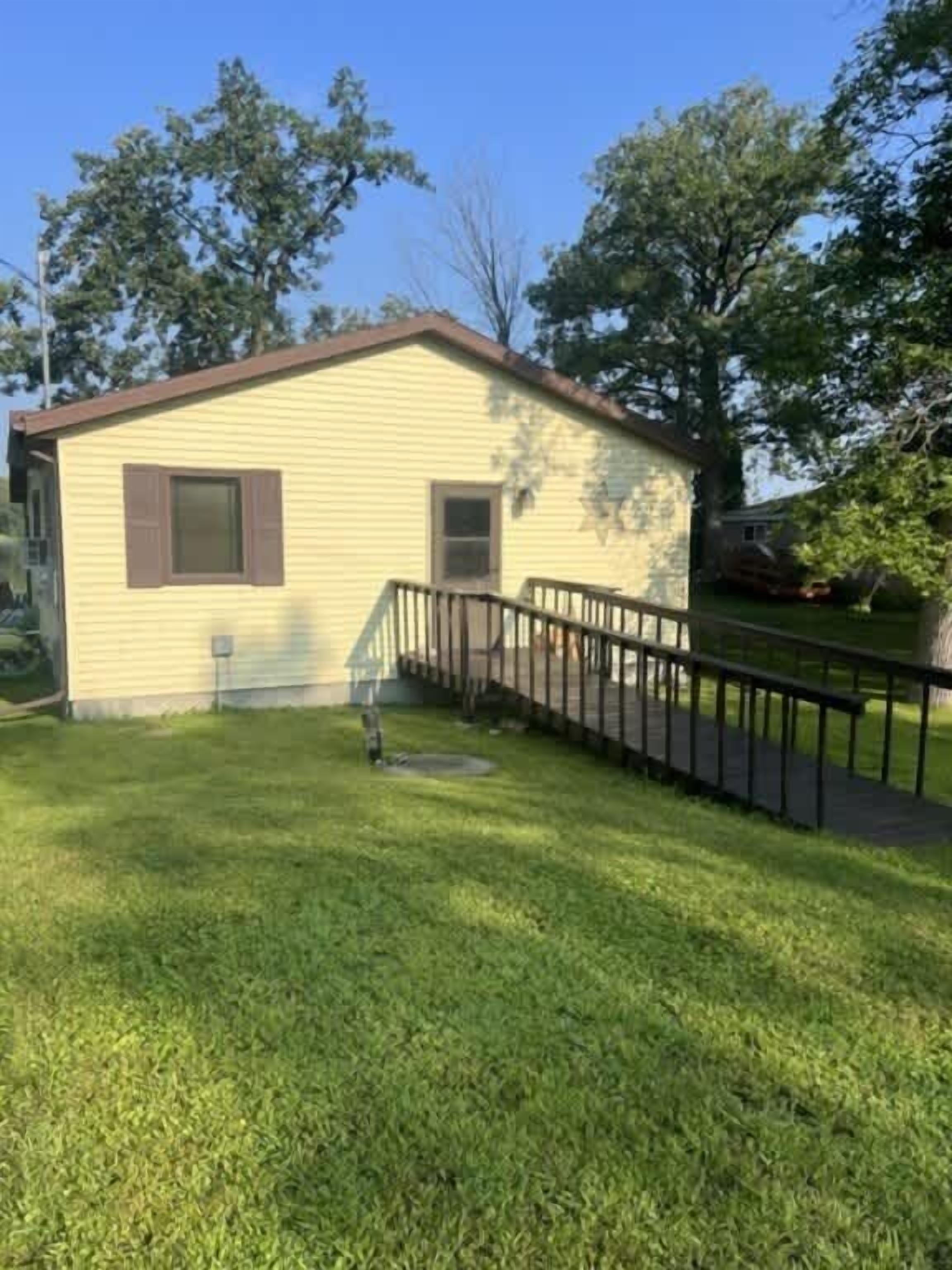 A small, single-story house with a front porch and a fenced yard.