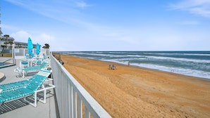 A beach with blue lounge chairs and umbrellas, a sandy shore, and the ocean. - Direct Oceanfront 2/2 | Private Balcony Overlooking the Pool | Garage Parking (Ormond Beach)