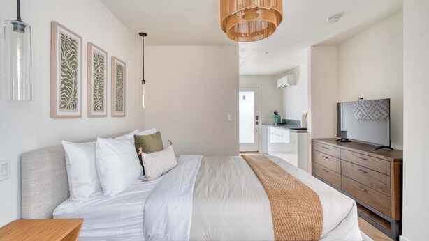 A bedroom with a bed, a wooden dresser, a television, and framed artwork on the wall. - Alberta Arts-tastic Mother-In-Law Suite (Portland)