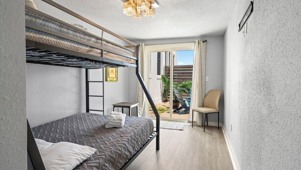 A compact bedroom with a bunk bed, a small table, and a chair. - Sinatra Cottage · Classic Charm by Ocean Town (Galveston)