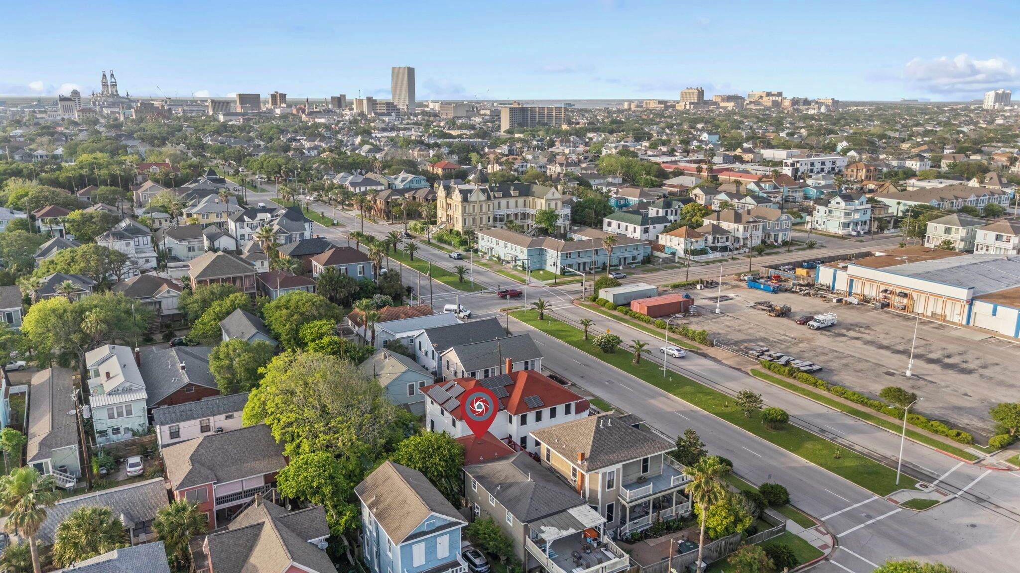 An aerial view of a residential area with houses, streets, and a large building in the background.