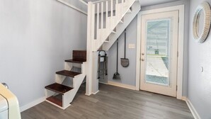 A staircase with wooden steps and white railings leading to a door with a window. - Sinatra Cottage · Classic Charm by Ocean Town (Galveston)