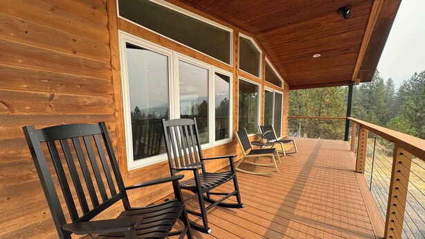 A wooden deck with outdoor seating and large windows.
