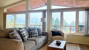 A spacious living room with a large window, a ceiling fan, and a view of the outdoors.