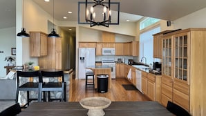 A modern kitchen with wooden cabinets, a central island, and pendant lighting.