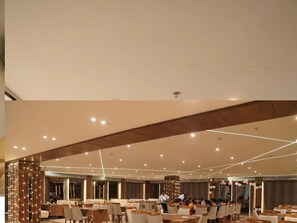A spacious banquet hall with multiple tables and chairs, a high ceiling with recessed lighting, and a modern architectural design. - Hotel Samdariya Gold - Rewa (Huzur)