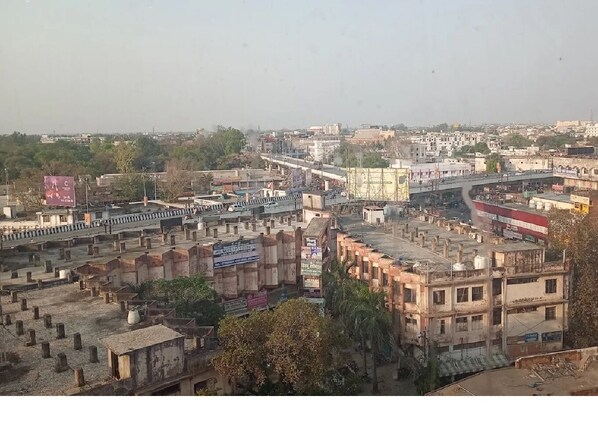 A view of a cityscape with a mix of residential and commercial buildings, a bridge, and a highway. - Hotel Samdariya Gold - Rewa (Huzur)
