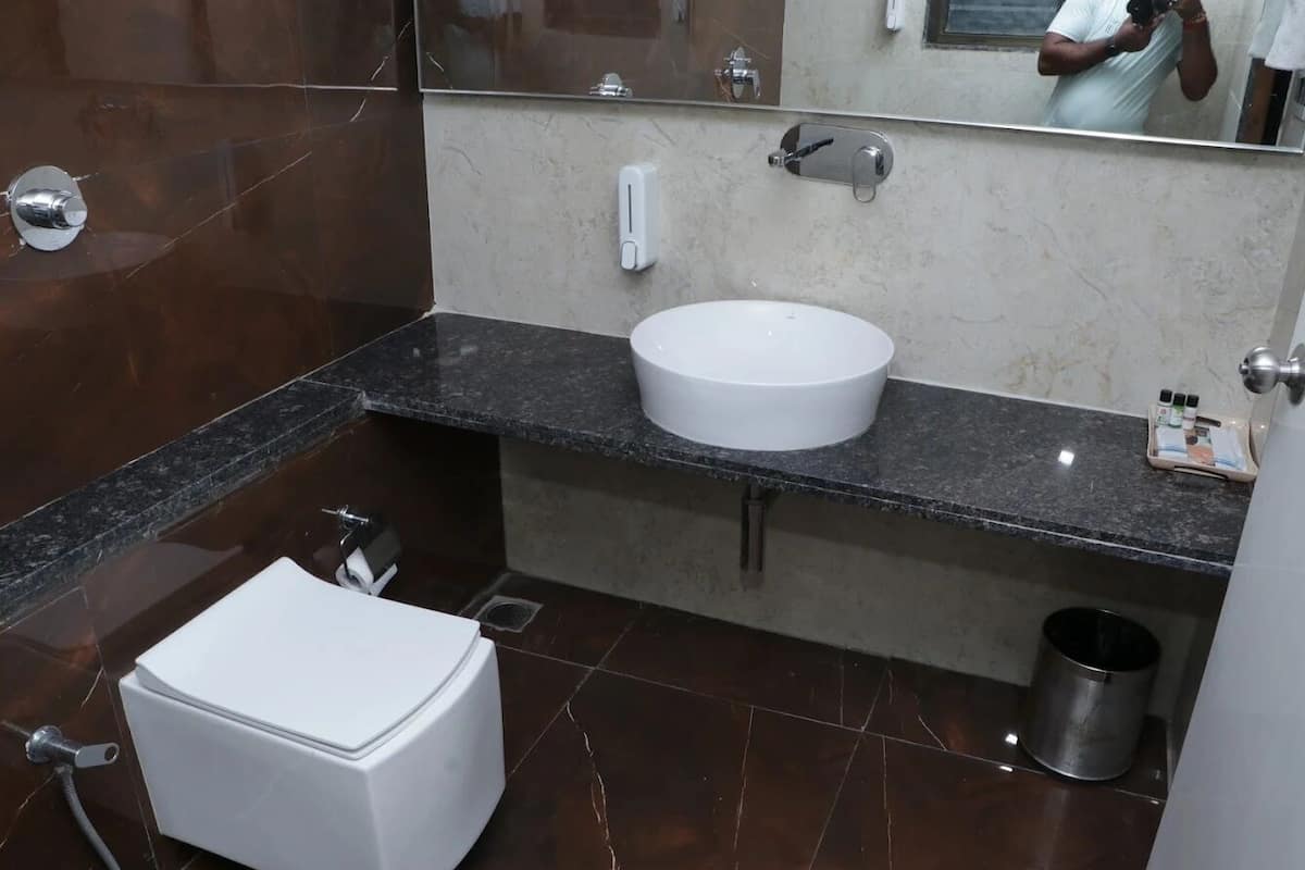 Ein modernes Badezimmer mit einer weißen Toilette, einem runden Waschbecken und einem Spiegel darüber.