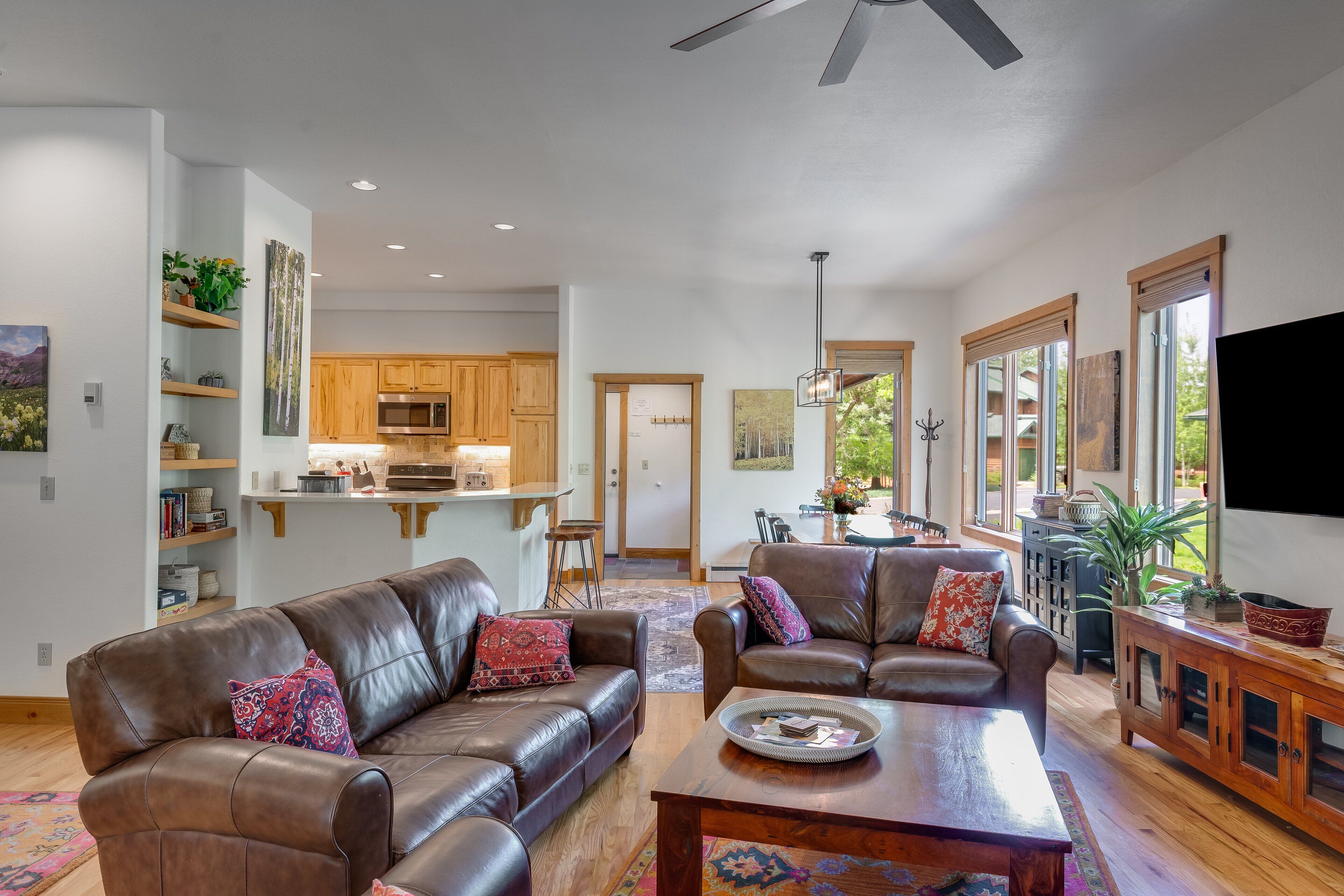 A spacious living room with leather sofas, a wooden coffee table, and a kitchen area in the background.
