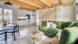 Una sala moderna con un sofá verde, una mesa de centro redonda y un comedor con mesa y sillas.