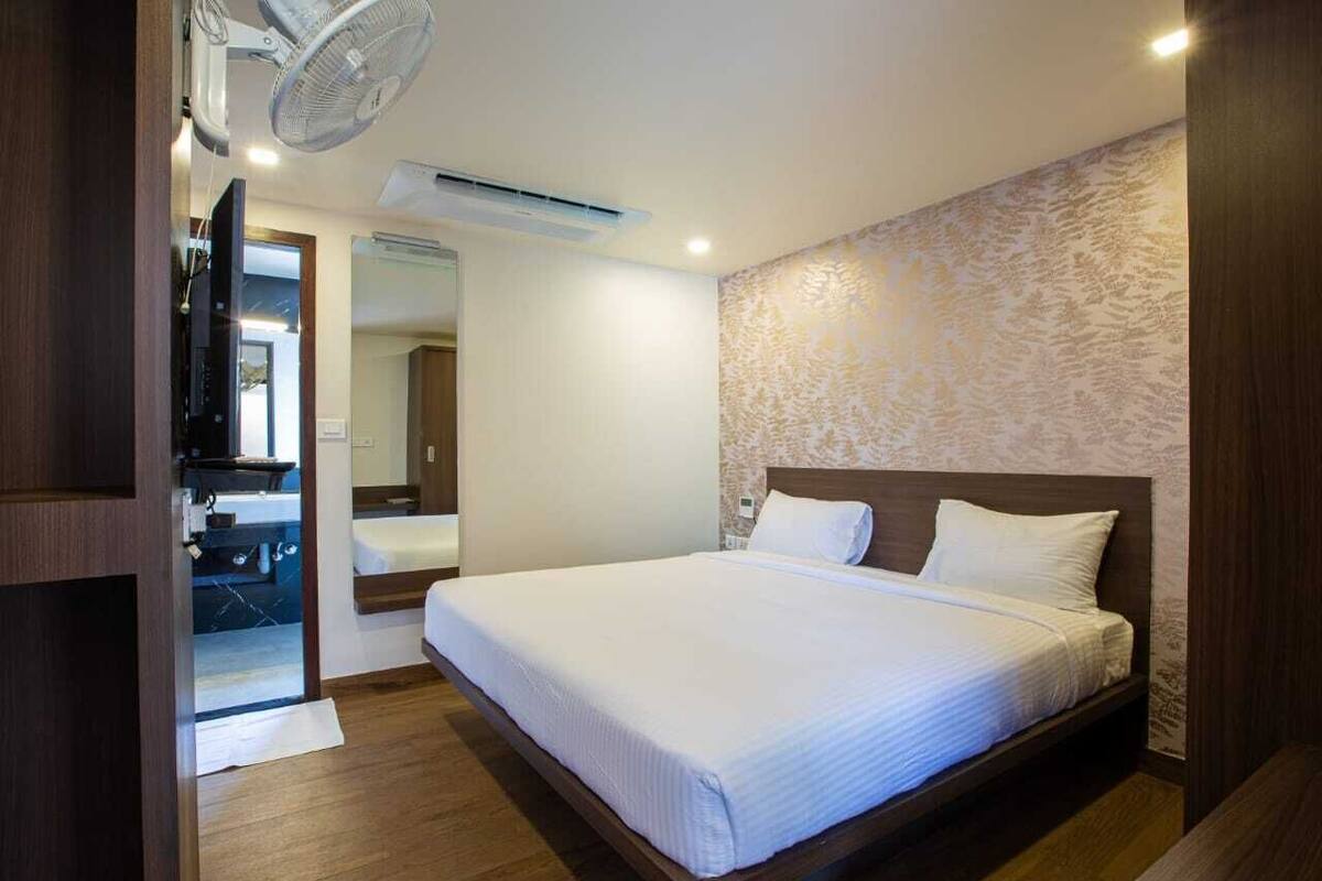 A bedroom with a bed, a wooden headboard, a wall-mounted air conditioner, and a ceiling fan.