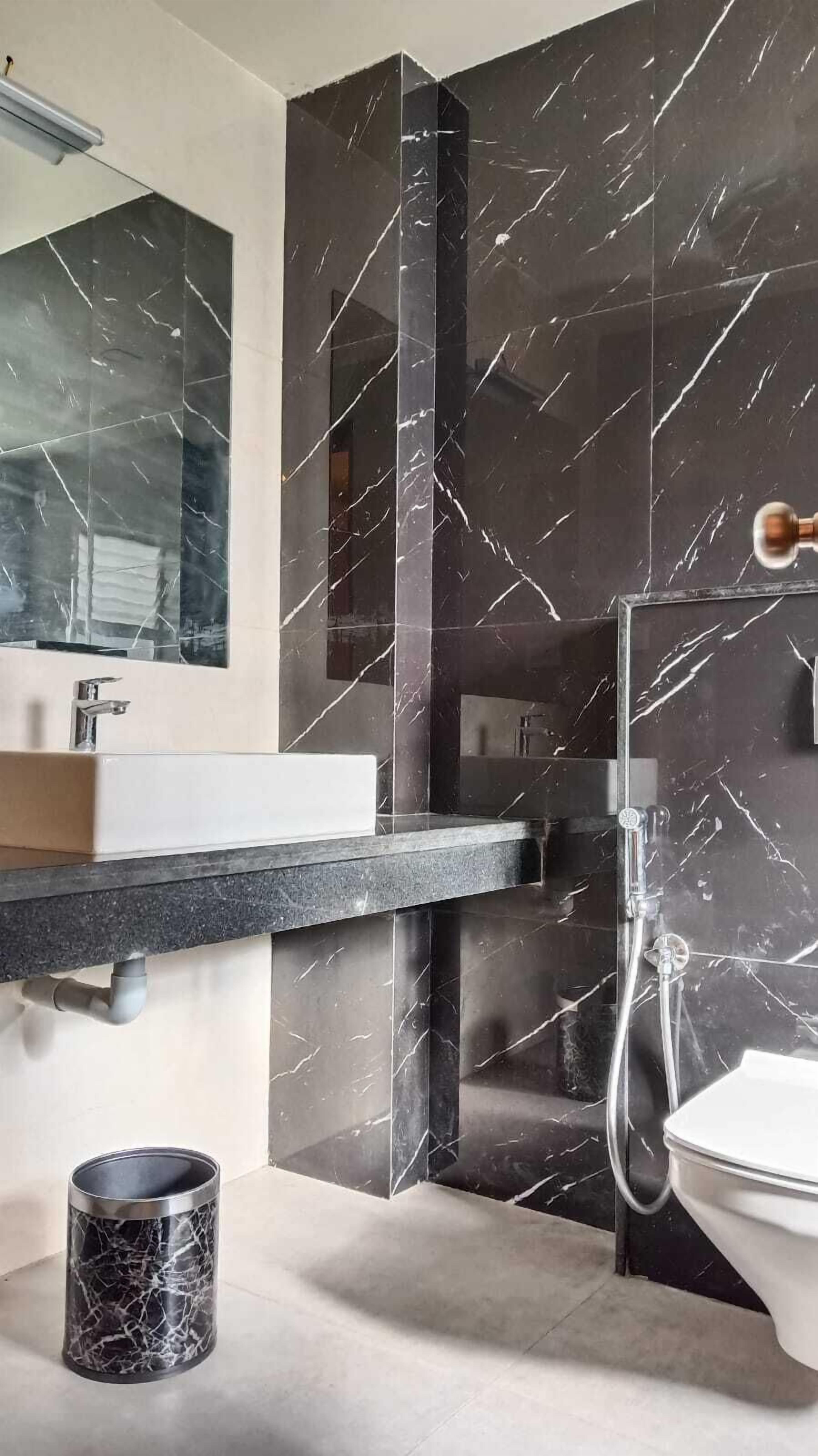 A modern bathroom with a marble sink, a mirror, and a shower.