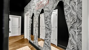 A hallway with black and white patterned walls, white doors, and wooden flooring.