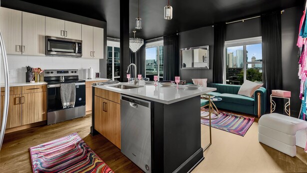 A modern kitchen with a central island, stainless steel appliances, and a large window offering a city view.