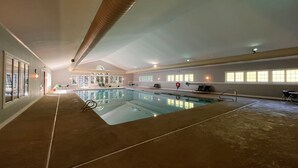Ein Innenpool mit klarem Wasser, umgeben von Liegestühlen und einem Teppichboden.