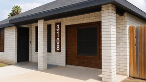 A modern two-story house with a brick facade, a dark roof, and a large front door. - Mayberry Cozy Home (Mission)