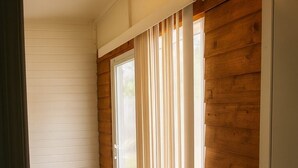 A hallway with wooden paneling, a sliding glass door, and a ceiling light fixture. - Mayberry Cozy Home (Mission)