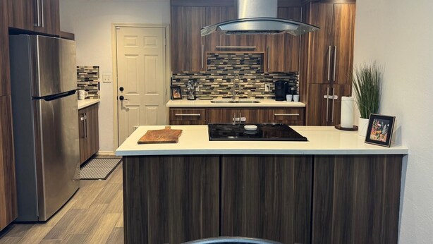 A modern kitchen with a central island, stainless steel appliances, and wooden cabinetry. - Mayberry Cozy Home (Mission)