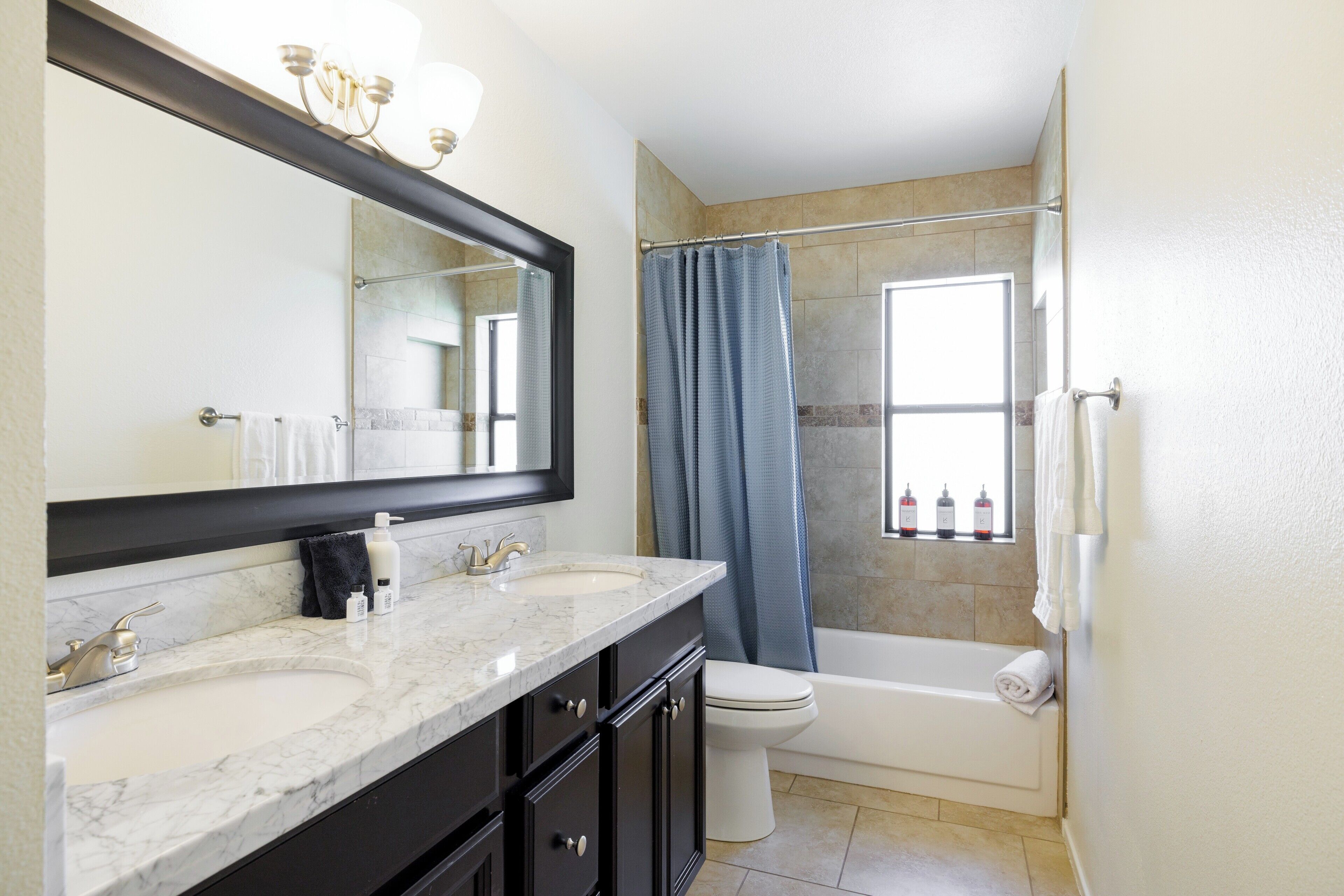 A bathroom with two sinks, a toilet, a bathtub, and a shower curtain.