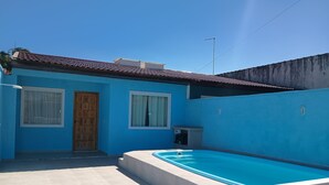Une maison bleue avec un toit en tuiles, une piscine et une porte avec une fenêtre.