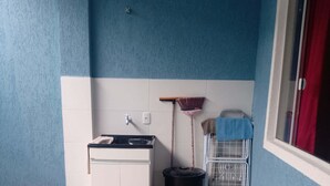 Un baño pequeño con un lavamanos blanco, un bote de basura negro y una cesta de ropa metálica.