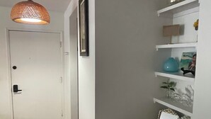 Ein Korridor mit Holzboden, einer weißen Tür, einem gerahmten Bild an der Wand und einem Regal mit Dekoration.