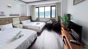 A hotel room with two beds, a desk, a TV, and a window with a view of the city. - HOTEL SON THINH VUNG TAU (Ho Chi Minh City)