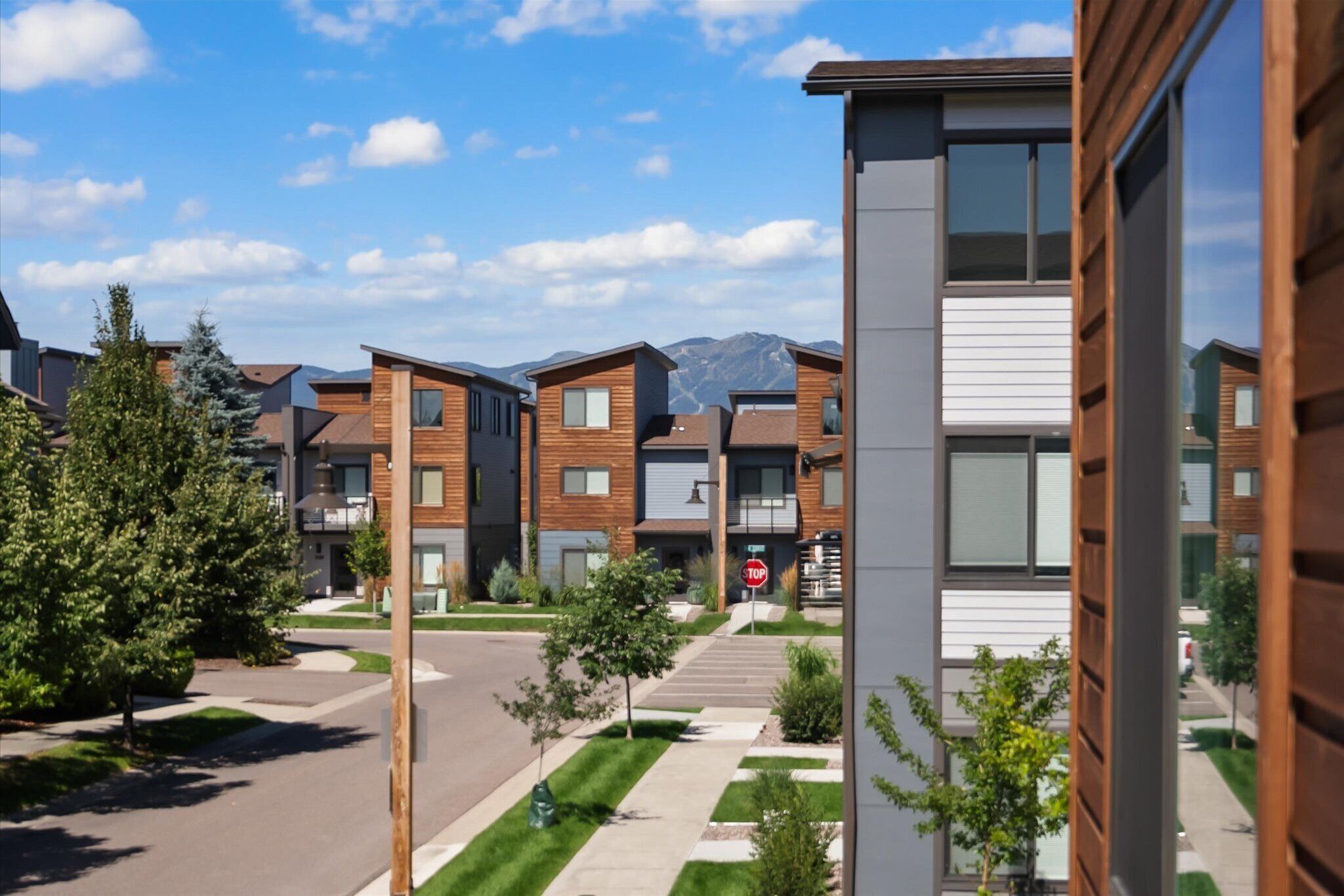 A modern residential area with multi-story buildings, a clear sky, and a mountain in the background.