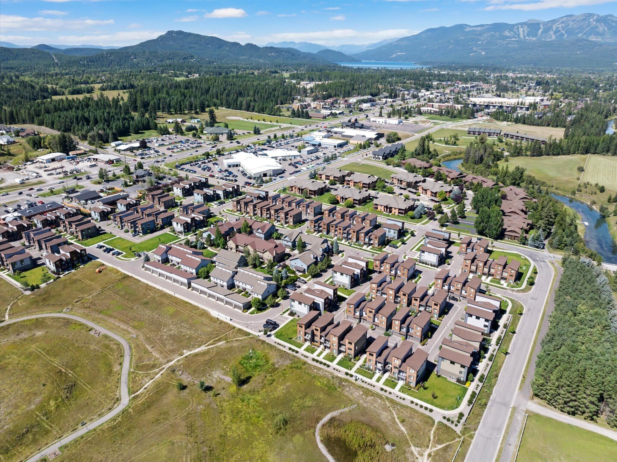 An aerial view of a residential area with detached houses, a large industrial building, and a river.