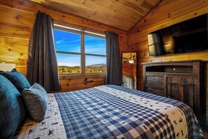 Une chambre dans un chalet en bois, avec un lit, des rideaux, une télévision et une cheminée.