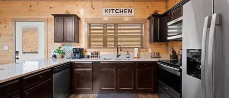 A modern kitchen with wooden cabinetry, a stainless steel refrigerator, and a window with blinds.