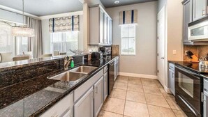 Een moderne keuken met granieten aanrechtbladen, roestvrijstalen apparatuur en een groot eiland met een spoelbak.