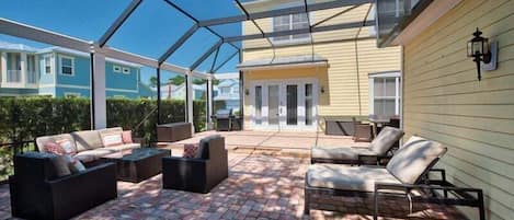 A covered patio with outdoor furniture, a glass ceiling, and a view of neighboring houses.