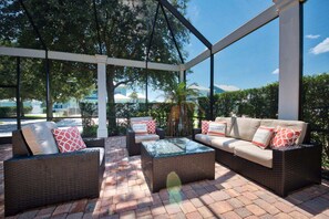 Une terrasse extérieure aménagée avec des meubles en osier, une table basse en verre et une vue sur les environs.