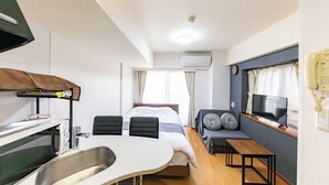 Une chambre d’hôtel de taille réduite, comprenant un lit, une télévision, une petite table à manger et une kitchenette.