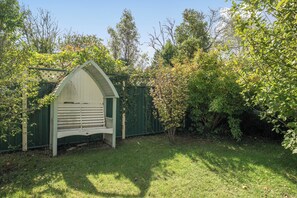 A garden with a wooden bench and a small shed.
