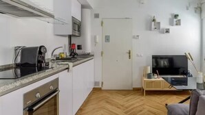 Una cocina compacta con microondas, cafetera y un lavamanos pequeño.