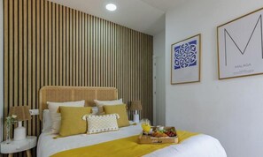 Een hotelkamer met een bed, nachtkastjes, een dienblad met ontbijt en twee kunstwerken in lijsten aan de muur.