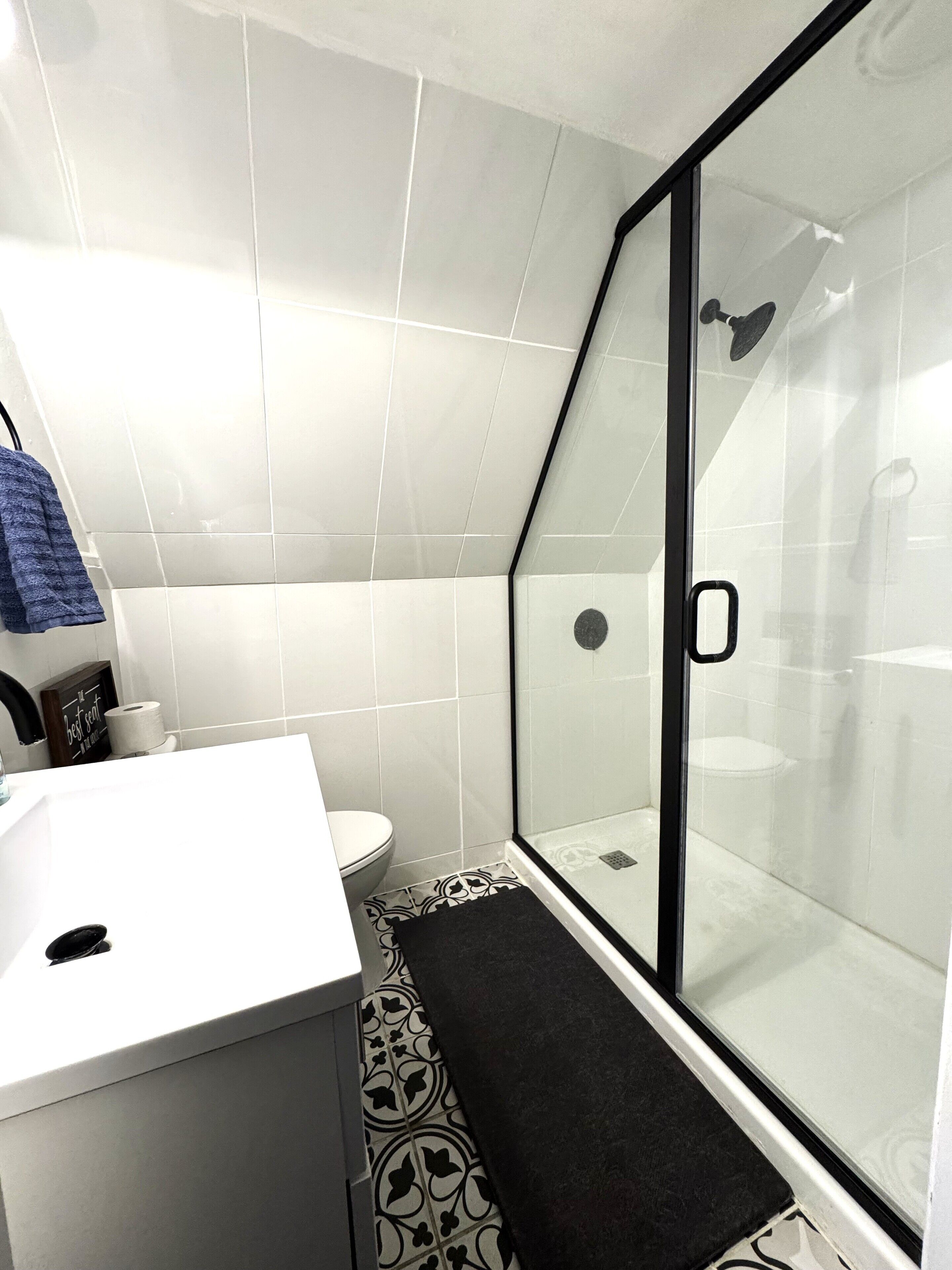 Un baño moderno con cabina de ducha de vidrio, un lavamanos blanco y un inodoro.
